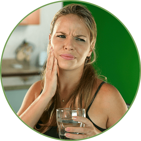 Female holding her cheek in pain after drinking a glass of water.